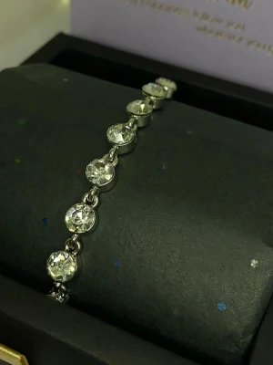 Silverfärgat armband med stora stenar - Snyggt armband i silverfärg med runda, klara stenar i rad. Stenarna är infattade i metall och ger ett glittrande och elegant intryck. Ej använd utan kommer från min small business.