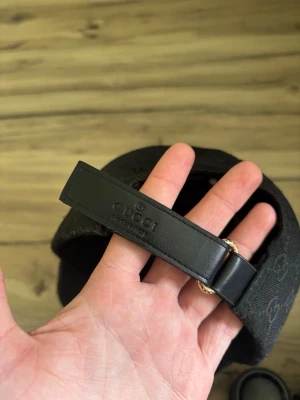Svart gg keps med påse - Svart gg keps med röd/gröna loggor på sidorna och ett spännband i bak. Påsen finns och följer självklart med ifall du vill ha den. Priset kan diskuteras!