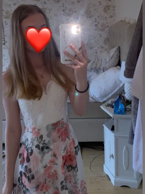 Blommig spetsklänning - Romantisk vit klänning med spets upptill och blommigt mönster i rosa toner. Klänningen har ärmlös design, v-ringad hals och lätt utsvängd kjol. Perfekt för sommarens alla tillfällen! Tyvärr har den blivit missfärgad på banden (se bilder, för fler bilder skriv privat) men kanske kan gå bort med rätt medel. Det är vaddering vid bysten och justerbara band baktill💓 Det finns en dragkedja i sidan också. 