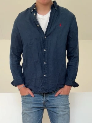 Mörkblå Ralph Lauren Linneskjorta  - Mörkblå Ralph Lauren Linneskjorta i bra skick utan nåra defekter. Barnstolen 18-20 vilket motsvarar vuxenstorlek S och sitter även som en S! Hör gärna av er vid frågor elr funderingar!!