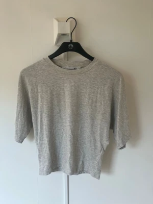 Ljusgrå basic t-shirt i bomull - En enkel och stilren ljusgrå t-shirt med rund hals och korta ärmar. Tillverkad i mjuk bomull för en bekväm känsla. Perfekt till jeans eller shorts för en avslappnad look.