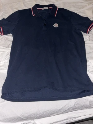 Marinblå pikétröja från Moncler - Hej säljer min blåa moncler pikee den är knappt använd har använt den 2 gånger den är i storlek M men passar bäst till S 