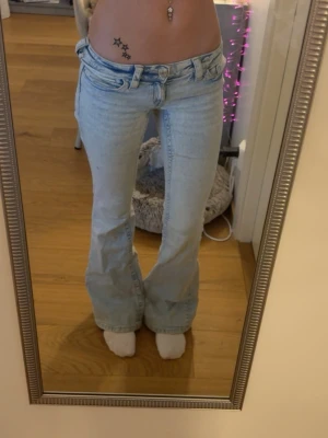 Ljusblå low waist bootcut jeans med brodyr - Säljer ett par ljusblå bootcut jeans med snygg brodyr på bakfickorna. Jeansen har låg midja och klassisk femficks design 