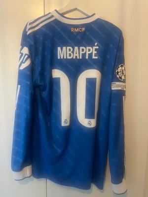 Äkta Real Madrid 25/26 LS tröja Mbappe - Äkta Real Madrid tredjetröja Long Sleeve från den här säsongen med Mbappe på ryggen. Aldrig använd eftersom att den var för stor i storleken på mig. Därmed inga defekter och nypris är 1700kr. Storlek L