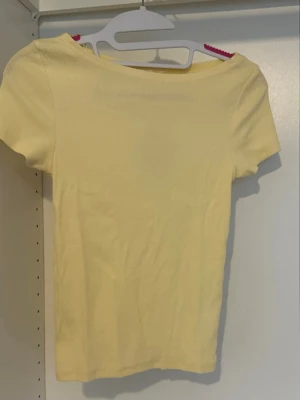 Ljusgul ribbad topp med kort ärm - Säljer en ljusgul ribbad topp med korta ärmar och rund hals. Toppen har en enkel och clean design som passar perfekt till jeans eller kjol. 