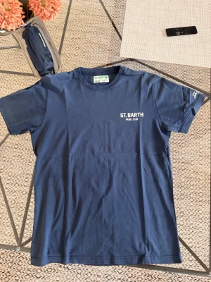 Mc2 Saint Bart ”Padel Club” T-shirt - Mörkblå t-shirt från St. Barth Padel Club med vit text och stort tryck på ryggen. Klassisk rund hals och korta ärmar. Tillverkad i mjuk bomull, perfekt för sportiga dagar eller chill vardagsstil.