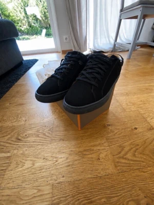 Svarta sneakers från Myrqvist - Stilrena svarta sneakers från Myrqvist i mocka med klassisk låg profil och svarta skosnören. Skorna har en diskret design som passar till det mesta och levereras med tygpåsar för förvaring. Perfekta för dig som gillar minimalistisk stil.