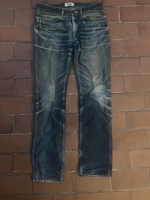 Acne jeans med slitningar - Säljer ett par klassiska blå jeans från Acne med snygga slitningar och faded detaljer på framsidan och baksidan. Jeansen har raka ben, fem fickor och är gjorda i kraftig denim. Perfekt för dig som gillar en cool och avslappnad look. storlek W32 L34