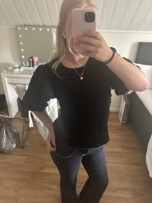 Svart puffärmad topp med struktur - Säljer en svart topp med coolt strukturerat tyg och puffiga korta ärmar. Toppen har en rund halsringning och är croppad i modellen. Perfekt för dig som vill ha något trendigt och unikt i garderoben! Aldrig använd💗