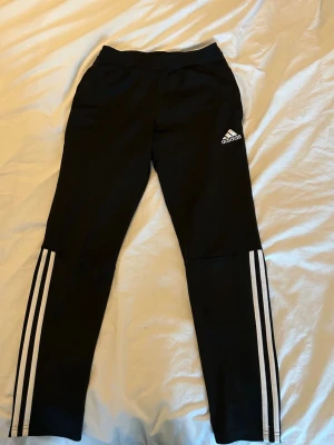 Svarta Adidas träningsbyxor - Svarta träningsbyxor från Adidas med klassiska vita ränder längs benen💕