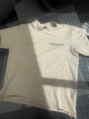  t-shirt - Snygg beige t-shirt med tryck både fram och bak. Klassisk passform med rund hals och korta ärmar. Perfekt för en clean och stilren look. Tillverkad i mjuk bomull för maximal komfort.