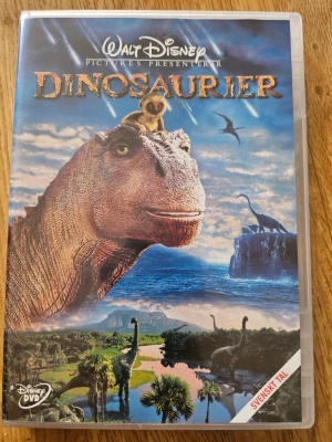 Disney DVD Dinousarier film - Säljer en Disney DVD med filmen Dinosaurier. Omslaget har färgglada illustrationer av dinosaurier och natur, och filmen har svenskt tal. Perfekt för dig som gillar animerade äventyr och klassiska Disneyfilmer.