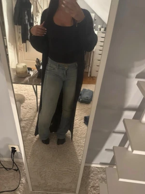 Ljusblå utsvängda jeans med låg midja - Säljer ett par ljusblå jeans med utsvängda ben och låg midja. Jeansen har klassiska fickor och stängs med två knapp och dragkedja. Perfekta för dig som gillar en avslappnad och trendig look.