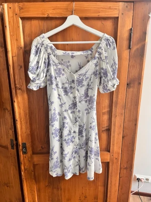 Ljuslila blommig klänning från MNG - Supersöt ljus klänning från MNG med lila blommor, puffärmar och knappar.