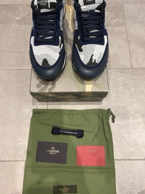 Blå vita Valentino Rockrunners  - Blåa Valentino Rockrunners använda nån gång. Det kommer med box, dustbags, extrasnören och ett kort från valentino. De är i storlek 43 men passar mellan 42-44. Ställ frågor vid funderingar! Priset är inte hugget i sten🚨