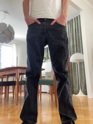 Svarta raka jeans från Nudie jeans, Rad Rufus - Säljer ett par svarta jeans från Nudie Jeans med klassisk femficksmodell och raka ben. Jeansen har normal midja och är tillverkade i ett slitstarkt bomullsmaterial. Perfekta för dig som gillar en tidlös och enkel stil. Man