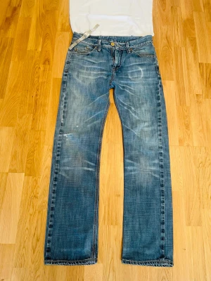 Blå raka/bootcut selvedge jeans från crocker med sjuka fades - Säljer ett par klassiska blå jeans från crocker med raka ben och snyggt slitna detaljer. Jeansen har gylf med knapp och dragkedja samt kontrastsömmar. Materialet är denim i bomull och passformen är rak/bootcut. Den har små slitningar som visas på bilderna, men jag tycker det ger dem mer karaktär. Storleken är 30/32, jag är 180cm, 72kg för referens. Jag fraktar snabbt! Skriv vid minsta fundering!