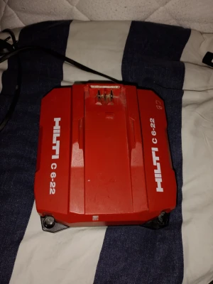 Hilti C 6-22 batteriladdare - Säljer en röd Hilti C 6-22 batteriladdare i robust plast. Laddaren har tydliga vita logotyper och modellbeteckning på ovansidan samt anslutningskontakter för batteri. Perfekt till dig som behöver ladda Hilti-verktygsbatterier. Den är i mycket fint skick och fungerar utan problem.  Nypris ligger runt 2000:-