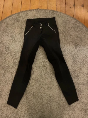 Svarta ridbyxor  - Säljer ett par svarta ridbyxor i storlek 34 (XS), säljer dessa pågrund av att de var för små för mig. På sista bilden kan man se att de är lite sönder, en tråd som lossnat vid benet. 