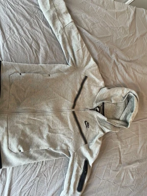 Nike tech  - Hej, säljer en grå Nike tech tröja i storlek  150-160 cm för barn. okej skick, men inga större skador på tröjan. Hör gärna av er om ni har några frågor om tröjan👍