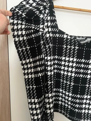 Svartvit rutig topp med puffärm - Trendig topp från Shein med svartvitt rutigt mönster och fyrkantig ringning. Långa puffärmar ger en cool siluett. Toppen är croppad och har en slim passform, perfekt till jeans eller kjol.