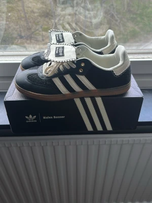 Adidas Wales Bonner svartvita sneakers - Snygga Adidas Wales Bonner sneakers i svart och vitt med klassiska tre ränder på sidan, beige snörning och unik detalj på plösen. Yttermaterial i läder och mocka, sula i gummi. Perfekta för dig som gillar stilrena men ändå unika skor. Lite använda dock säljs billigt för användning 