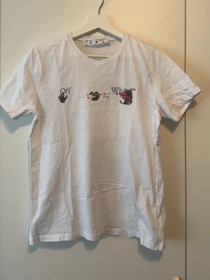 Vit t-shirt med tryck - Vit t-shirt från med unikt grafiskt tryck i svart och vinrött på både fram- och baksidan, klassisk rund hals och korta ärmar. Säljer eftersom den ej kommer till användning.