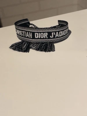 Svart broderat armband Dior - Snyggt svart och vitt broderat armband från Christian Dior med texten 'J'ADIOR⬛️⬜️ eftersom jag hade redan ett och vill gärna få den såld. Kom med bud⭐️