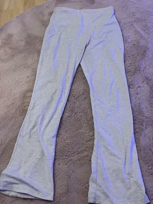 Grå utsvängda leggings - Snygga grå leggings med utsvängda ben och hög midja. Mjukt och stretchigt material som sitter skönt på kroppen. Perfekta för en avslappnad och trendig look.  (ett litet hål i sömnen men det är lätt att dunk.)