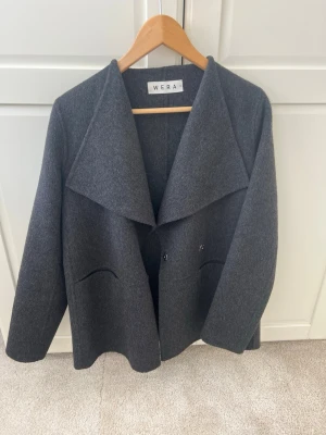 Mörkgrå ullkappa från Wera - Sååå fin och Stilren mörkgrå kappa från Wera! Säljer då den tyvärr är för liten för mig🥲 Perfekt tunn nu till vår men även hösten♥️Nypris 2000 kronor och i princip oanvänd!