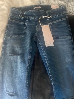 Blå bootcut jeans med slitningar - Säljer dessa helt nya plated flair jeans från Gina tricot i storlek XS