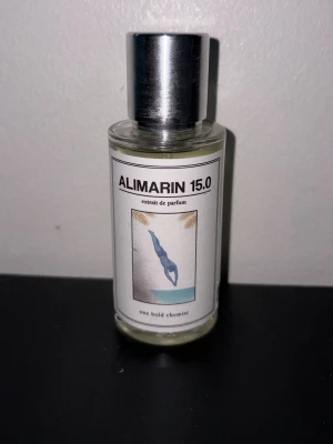 Alimarin 15.0 parfym One Bold Chemist - Alimarin 15.0 är en exklusiv parfym från One Bold Chemist. Flaskan är genomskinlig med en silverfärgad metallkork och har en stilren etikett med en illustration av en dykare. Parfymen har en modern och minimalistisk design som passar perfekt på hyllan.