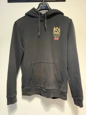 Svart hoodie från Morris med tryck - Svart hoodie från Morris med guldfärgat emblem och brittisk flagga på bröstet. 