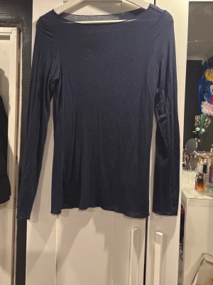Mörkblå långärmad topp Intimissimi - En tunn och mjuk mörkblå långärmad topp från Intimissimi. Toppen har en enkel, klassisk design med rund halsringning och är tillverkad i ett stretchigt material som sitter skönt mot kroppen.