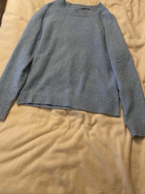 Ljusblå stickad tröja Vero Moda - Mysig ljusblå stickad tröja från Vero Moda med rund halsringning och ribbade muddar vid ärmslut och nederkant. Perfekt för kyliga dagar och enkel att matcha med jeans eller kjol.