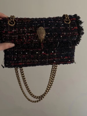 Kurt Geiger Kensington axelväska - Säljer en Kurt Geiger Kensington axelväska med grov kedja i antikguld och snyggt rutigt tyg i mörka toner.  Perfekt storlek för det viktigaste. 