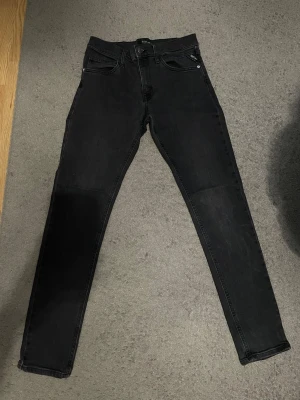 Svarta skinny jeans från replay  - Snygga svarta skinny jeans från replay med klassisk femficksdesign och diskret logga på bakfickan. Jeansen har en smal passform och är tillverkade i ett stretchigt denimtyg som sitter tajt längs benen. Perfekta för en trendig och avslappnad look. Storleken är 14 A sitter som w 28/29 L 30