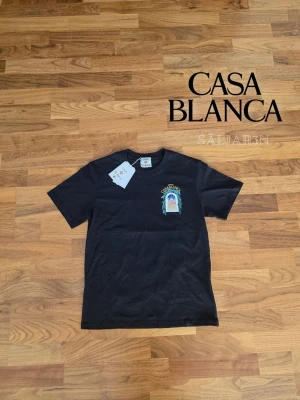 CasaBlanca T-Shirt - 🖤 Casa Blanca T-shirt – Svart | Storlek M 🖤  Stilren och exklusiv t-shirt från Casa Blanca med färgglad grafik på både framsidan och baksidan. Tillverkad i mjukt material som ger en bekväm passform och ett konstnärligt uttryck. Perfekt för att ge din vardagsstil en premium touch. T-shirten är i nyskick och kommer med originaltaggar.  ✨ Detaljer: • Storlek: M (lite liten i storleken) • Nytt skick med taggar  📦 Snabb leverans 📩 Kontakta mig vid frågor!