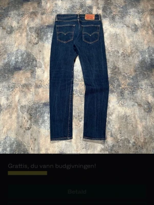 Levi's 512 mörkblå raka jeans - Säljer ett par klassiska Levi's 512 jeans i mörkblå denim med raka ben och kontrastsömmar. Jeansen har två bakfickor med den ikoniska V-sömmen och läderpatch i midjan. Perfekta för en avslappnad och tidlös stil. 28/3