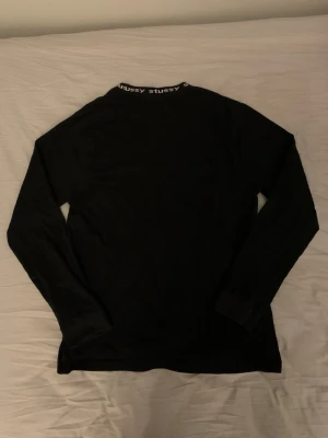 Stussy Jacquard long sleeve  - Svart långärmad tröja från Stussy med rund halsringning och Stussy-logga tryckt runt kragen. Enkel och stilren design, perfekt för en avslappnad streetwear-look. Priset är inte hugget i sten så kom gärna med bud!