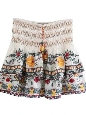 Vit broderad kortkjol med volang - Superfin vit kortkjol med broderade blommor i grönt, gult och rött. Kjolen har smock i midjan, volang och färgglada detaljer. Från Zara 