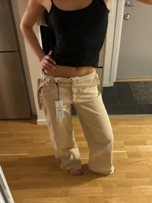 Ginatricot jeans - Säljer ett par beige jeans från ginatricot med lös passform och hög midja. Jeansen har breda ben, bälte i samma material och klassiska fickor både fram och bak. Perfekta för en avslappnad och trendig stil. Har storlek 34 också med prislappar kvar💞