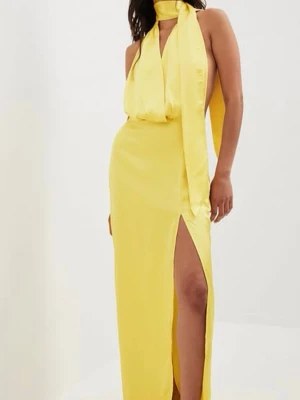 Gul långklänning med slits och scarf - Snygg gul långklänning i satinliknande material med hög slits och scarf-detalj runt halsen. Ett litet märke på ena bandet men det är den enda defekten som jag har sett.