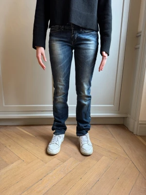 Mörkblå raka jeans med slitningar - Snygga mörkblå jeans med raka ben och coola slitningar framtill. Jeansen har klassiska fem fickor och kontrastsömmar. Perfekta för en avslappnad streetstil. Materialet är denim med lite stretch för extra komfort. Storlek W27 L32 Trendiga Replay jeans med snygga slitningar och markerad tvätt. Unik bakficka med dragkedja och Replay-detaljer som sticker ut. Smal passform som framhaver benen utan att kännas för tight. Ett statement-plagg som lyfter en enkel outfit direkt. Modellen är 160 cm lång och