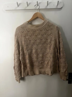 Beige stickad tröja med mönster - Säljer en beige stickad tröja med snyggt strukturmönster och ribbade muddar vid ärmslut och nederkant. Tröjan har rund halsringning. Är M men funkar för S och kanske XS.