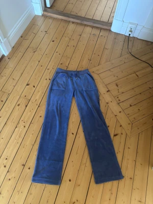 Blå mjukisbyxor med fickor - Säljer ett par blå mjukisbyxor i mjuk velour med bred resår i midjan. Byxorna har raka ben och stora fickor framtill. Perfekta för chill dagar och riktigt sköna att ha på sig.