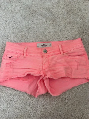Rosa shorts från Hollister - Snygga rosa shorts från Hollister med fransig kant och slitna detaljer. Klassisk femficksmodell med knapp och dragkedja framtill. Perfekta för varma dagar och ger en avslappnad vibe.💓