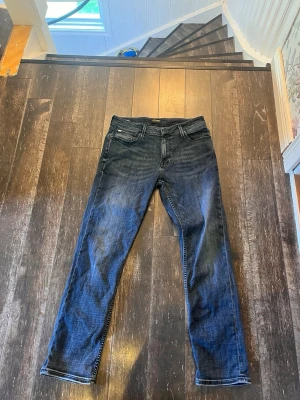 Mörkblå raka jeans - Snygga mörkblå jeans med raka ben och klassisk femficksmodell. Jeansen har kontrastsömmar och en diskret tvättad look som ger en avslappnad vibe. Passar perfekt till en enkel t-shirt eller hoodie för en casual stil. Materialet är lite stretchigt. Har använts någon gång bara. Skriv om du har några frågor. Pris kan diskuteras.