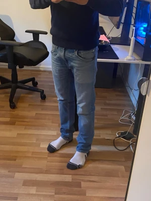 Ljusblå raka jeans herr - Säljer ett par ljusblå jeans med rak passform och klassisk femficksdesign. Jeansen har normal midja och är tillverkade i denim med lätt tvättad look. Perfekta till vardags för en avslappnad stil. Sitter slim använda med slitningar men fyller funktionen.
