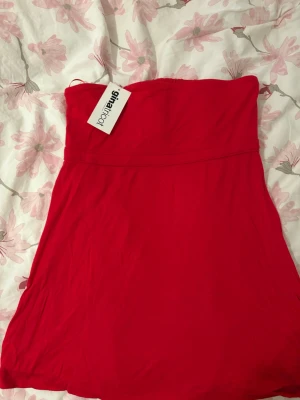 Röd openback tröja från Gina Tricot - Röd tubklänning från Gina Tricot i mjukt material. Klänningen är axelbandslös och har en kort längd, perfekt för varma dagar. Enkel och stilren design med lätt rynkad överdel som är openback HELT NY!.